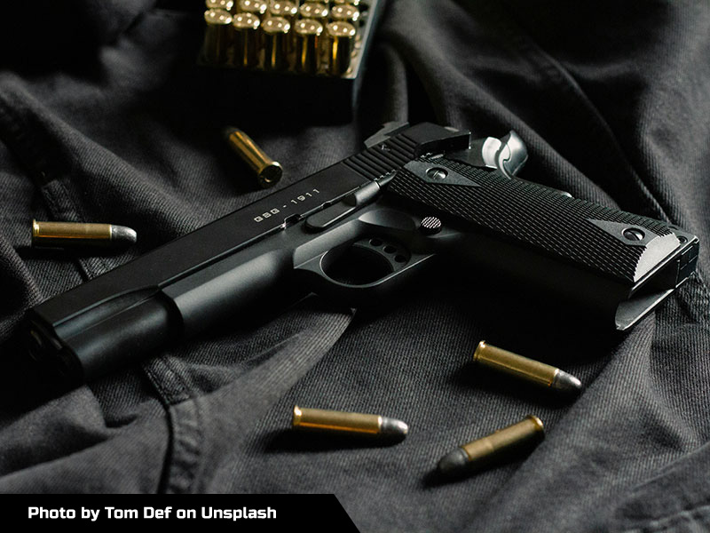 Image of a 1911 pistol on a table next to ammo